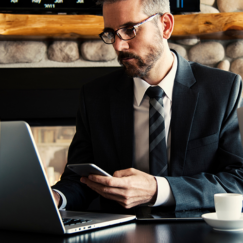 Businessman banking on his phone and laptop.